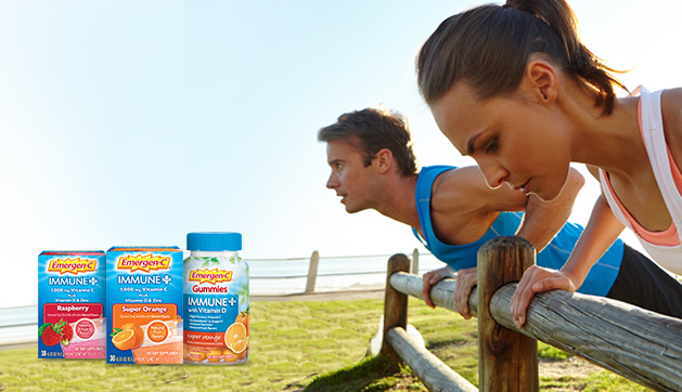 Emergen-C Immune Plus products. A man and woman wearing athletic apparel, leaning on a wooden fence to stretch.