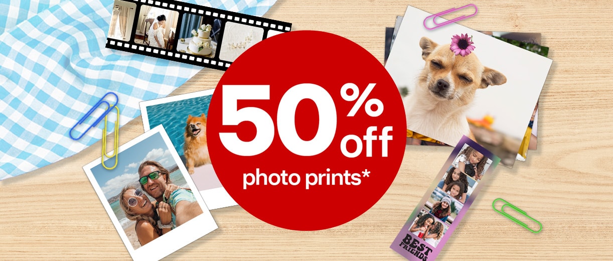 50% off photo prints. Images of printed family and pet photos scattered on a wooden surface with a checkered blue tablecloth and paper clips