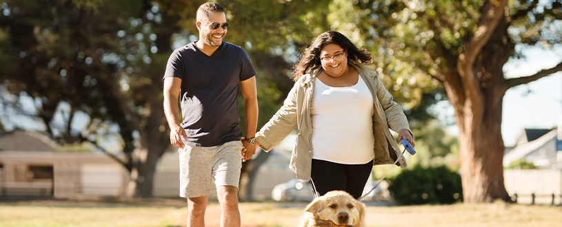 A couple on a walk holding hands with their dog