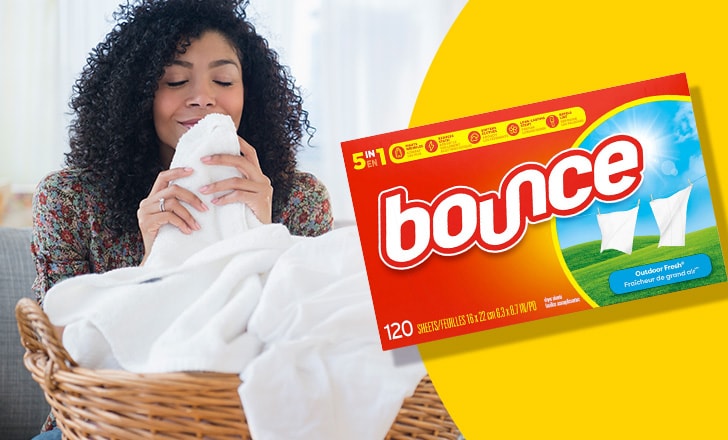 Bounce laundry sheets next to a woman smiling as she smells fresh white towels in a woven basket